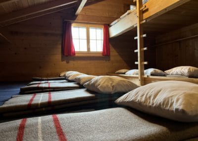 Schlafzimmer mit 17 Betten, Wolldecken und Kissen.
