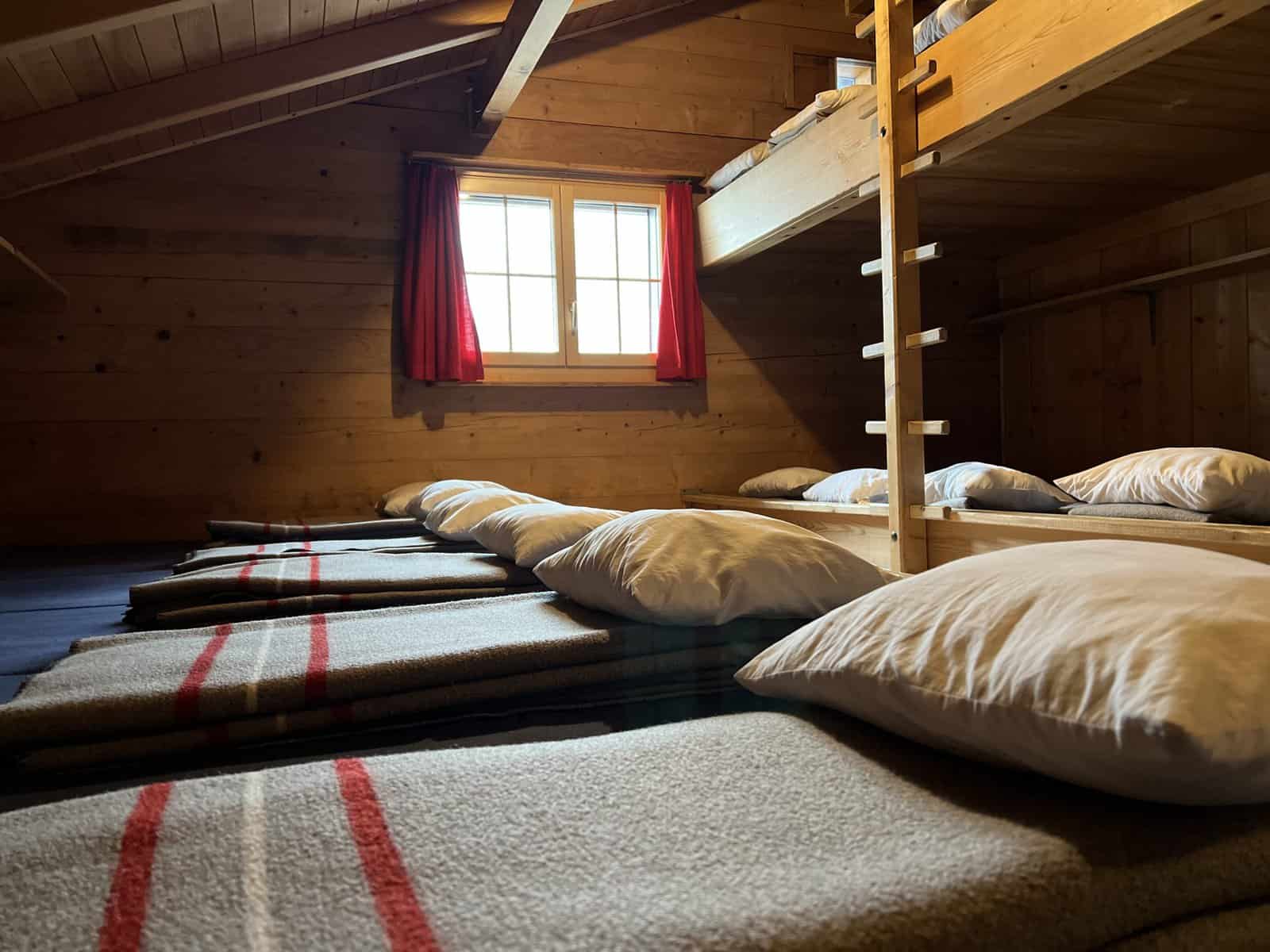 Schlafzimmer mit 17 Betten, Armeedecken und Kissen.